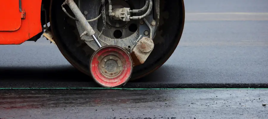 Heavy compactor tires the upper layer of asphalt in the construction of a parking lot for tourist buses