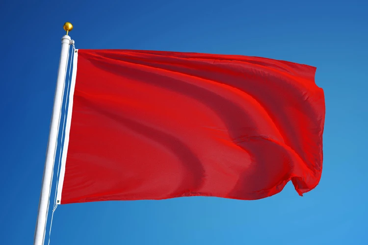 Bright red flag waving against a blue sky, symbolizing warning signs and red flags homeowners should watch for when hiring a New Jersey paving contractor.