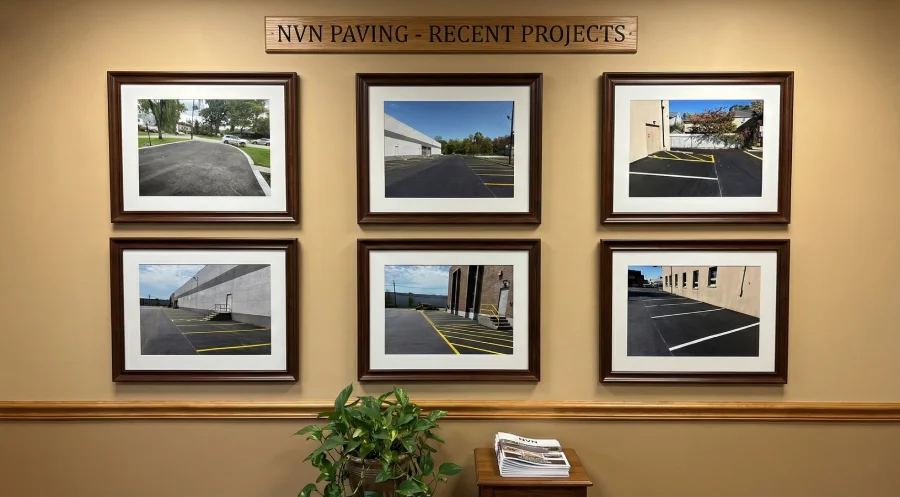 A photo of the 'NVN PAVING - RECENT PROJECTS' framed photo wall in their office, displaying pictures of completed commercial and residential asphalt paving and parking lot striping jobs.